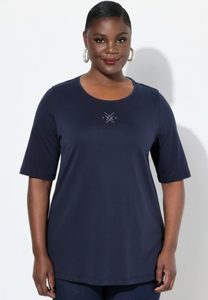 Chemise bleu marine à manches courtes avec un col rond, présentant un design géométrique au centre. Tissu doux et lisse avec une coupe décontractée.