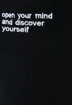 Tessuto nero con testo ricamato bianco che recita: "apri la tua mente e scopri te stesso", con una superficie liscia.