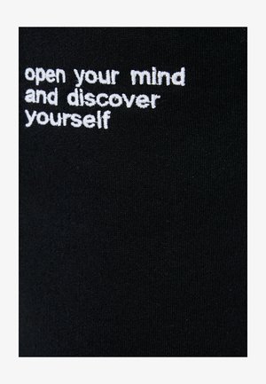 Tessuto nero con testo ricamato bianco che recita: "apri la tua mente e scopri te stesso", con una superficie liscia.
