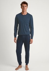 Navy blauwe pyjama set met een geblokte lange mouwen top met een zak en bijpassende taps toelopende broek, gemaakt van zachte, rekbare stof.