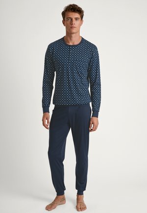 Marineblaues Schlafanzugset mit einem gemusterten Langarmoberteil mit Tasche und passenden schmal zulaufenden Hosen, gefertigt aus weichem, dehnbarem Stoff.