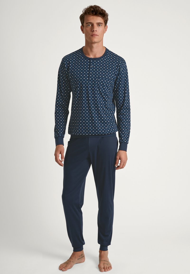 Navy blauwe pyjama set met een geblokte lange mouwen top met een zak en bijpassende taps toelopende broek, gemaakt van zachte, rekbare stof.