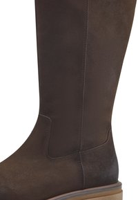 Bota de cuero marrón hasta la rodilla con una superficie texturizada, sutiles detalles de costura y una suela baja y plana para mayor comodidad.