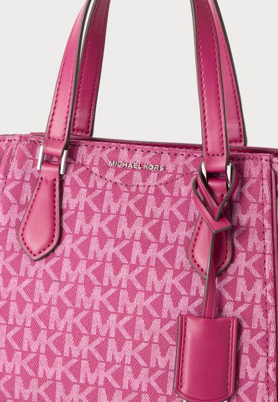 Розова дамска чанта Michael Kors с повтарящ се модел на логото MK, двойни дръжки и детайл от кожен етикет в близък план.