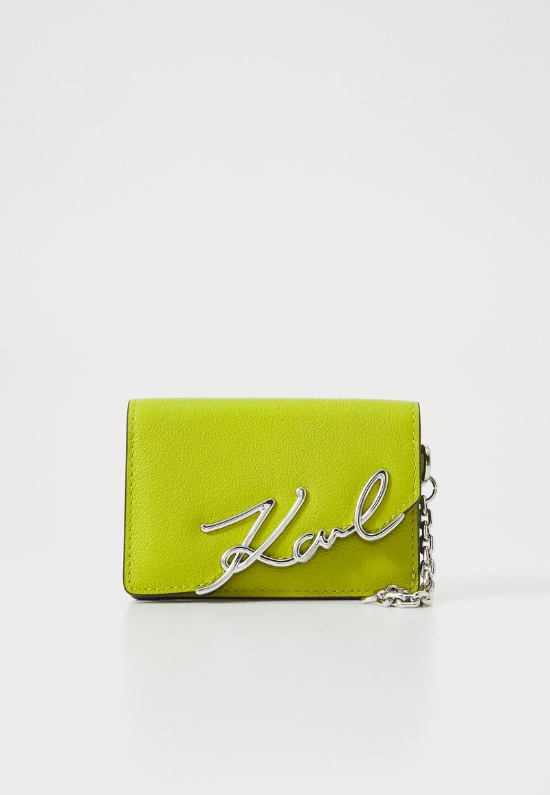 Lime green leather wallet with silver metal chain and signature "Karl" logo in cursive. Rectangular shape with textured surface.