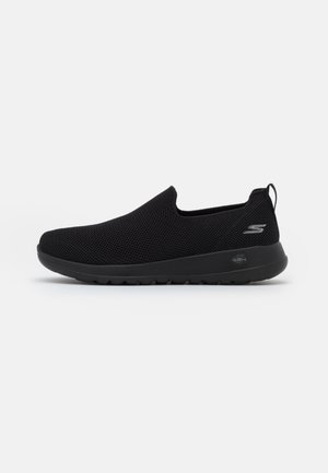 Matalavartiset mustat slip-on-tennarit verkkopäällisellä, pehmustetulla pohjalla, kantapäässä vetolenkillä ja Skechers-logo sivussa ja pohjassa.