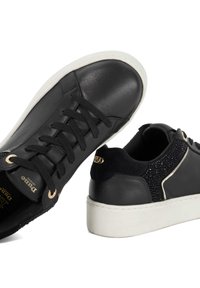 Black leather sneakers featuring a textured back panel with shiny accents, white rubber sole, and black laces. Gold hardware detail visible.