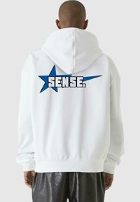 White hoodie featuring a large blue star and the word "SENSE." printed on the back. Soft, casual material with a relaxed fit.