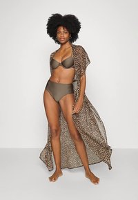 Kimono com estampa de leopardo em tecido transparente, usado sobre um conjunto de bikini verde-oliva. O design apresenta mangas fluídas e um ajuste descontraído.