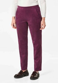 Paarse faux suède broek met een aansluitend ontwerp, voorzien van zijzakken en een gladde textuur, gecombineerd met donkere gepolijste schoenen.