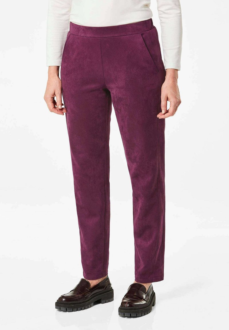 Paarse faux suède broek met een aansluitend ontwerp, voorzien van zijzakken en een gladde textuur, gecombineerd met donkere gepolijste schoenen.