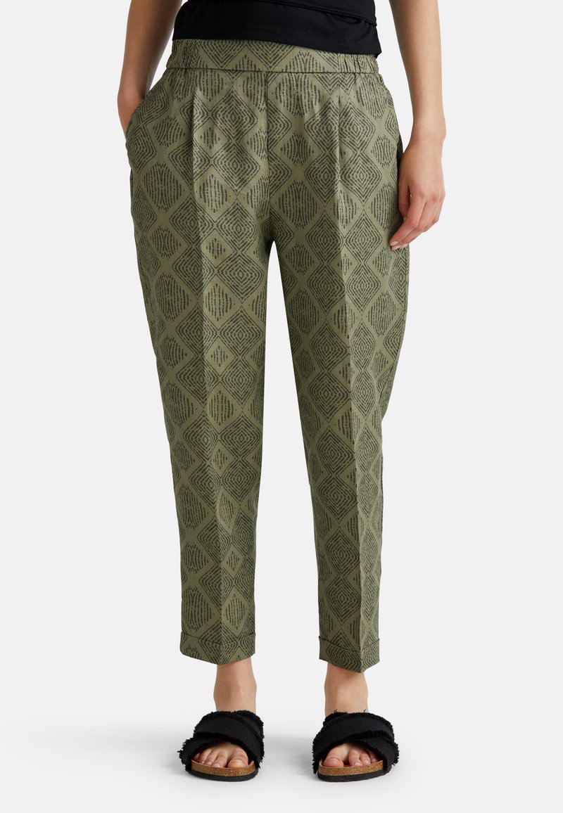 Zelené kalhoty s diamond potiskem, tapered střih, přední skladby a boční kapsy, doplněné černými chlupatými sandály.