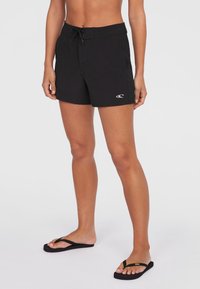 Sorte svømmeshorts laget av lett materiale, med elastisk midje og en subtil logo. Glatt tekstur, knelengde design.
