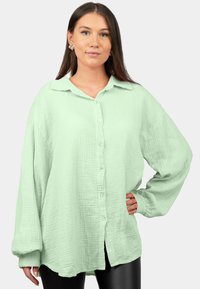 Camicia button-up verde chiaro realizzata in tessuto testurizzato, con colletto, maniche lunghe e una vestibilità rilassata con orlo arrotondato.