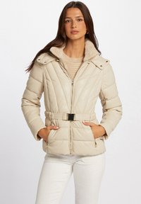 Giacca puffer beige con cintura in vita, chiusura zip e colletto in pelliccia sintetica. Presenta una texture trapuntata e tasche laterali. Accentuata da hardware dorato.