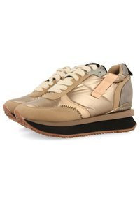 Zapatillas metalizadas en color beige con cordones color marfil, suela marrón en contraste, parte superior de cuero y detalles sintéticos. Con un acabado texturizado y detalle de logo.