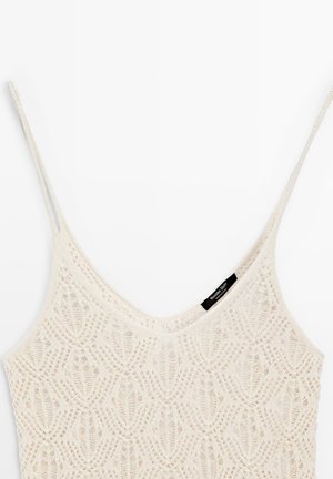 Crèmekleurige gehaakte tanktop met dunne bandjes en een V-hals, met een delicaat opengewerkt patroon en een klein zwart merkje.