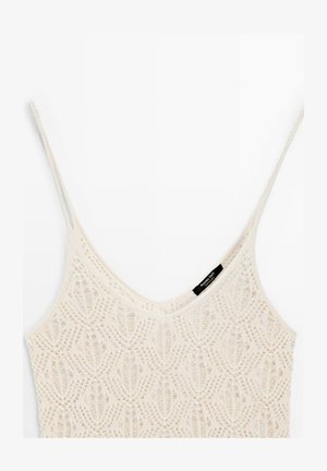 Crèmekleurige gehaakte tanktop met dunne bandjes en een V-hals, met een delicaat opengewerkt patroon en een klein zwart merkje.