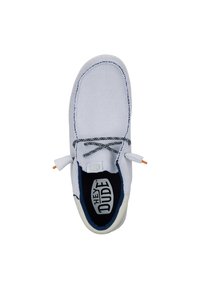Zapatilla de lona blanca con costuras azules en contraste, cordones negros y suela de goma. Presenta una plantilla acolchada con logo.