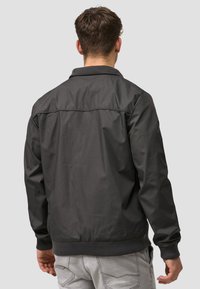 Black, lightweight bomber jacket with ribbed collar and cuffs. Smooth texture and simple design, featuring a subtle back seam detail.
