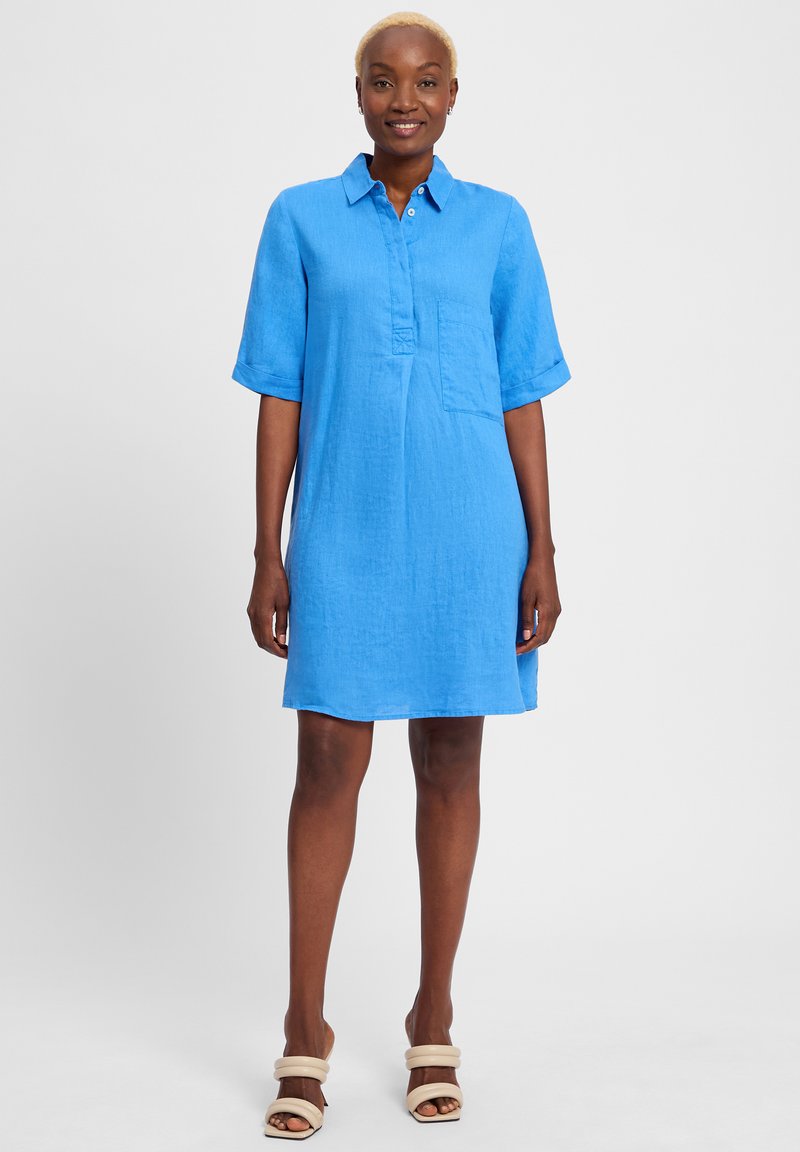 Blaues Leinenhemdkleid mit Kragen, kurzen Ärmeln, einer Brusttasche und einem lässigen Schnitt. Der Stoff hat eine strukturierte Oberfläche.