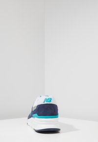 Kengät juoksuun, tummansinistä ja valkoista mokkaa, jossa on verkkopinta, turkoosi yksityiskohtia ja logo kantapäässä, sekä pehmustettu pohja.