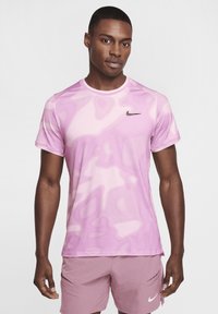 Camiseta deportiva para hombre de Nike en color rosa con un patrón ondulado, mangas cortas, escote redondo y un pequeño logotipo negro en el pecho. Textura suave.