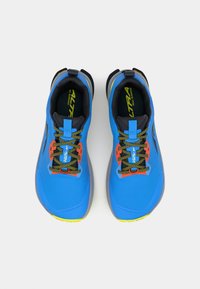 Des chaussures de trail running bleues présentent un dessus texturé, des semelles grises contrastantes, des lacets multicolores et un branding bien visible sur la languette.