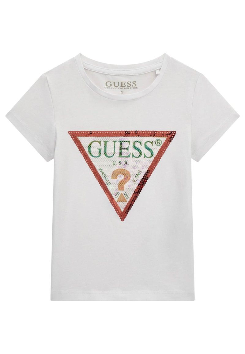 Valkoinen puuvillapaita, jossa on suuri kolmionmuotoinen logo paljeteista vihreillä ja punaisilla yksityiskohdilla, sekä "GUESS U.S.A." -teksti sisällä.