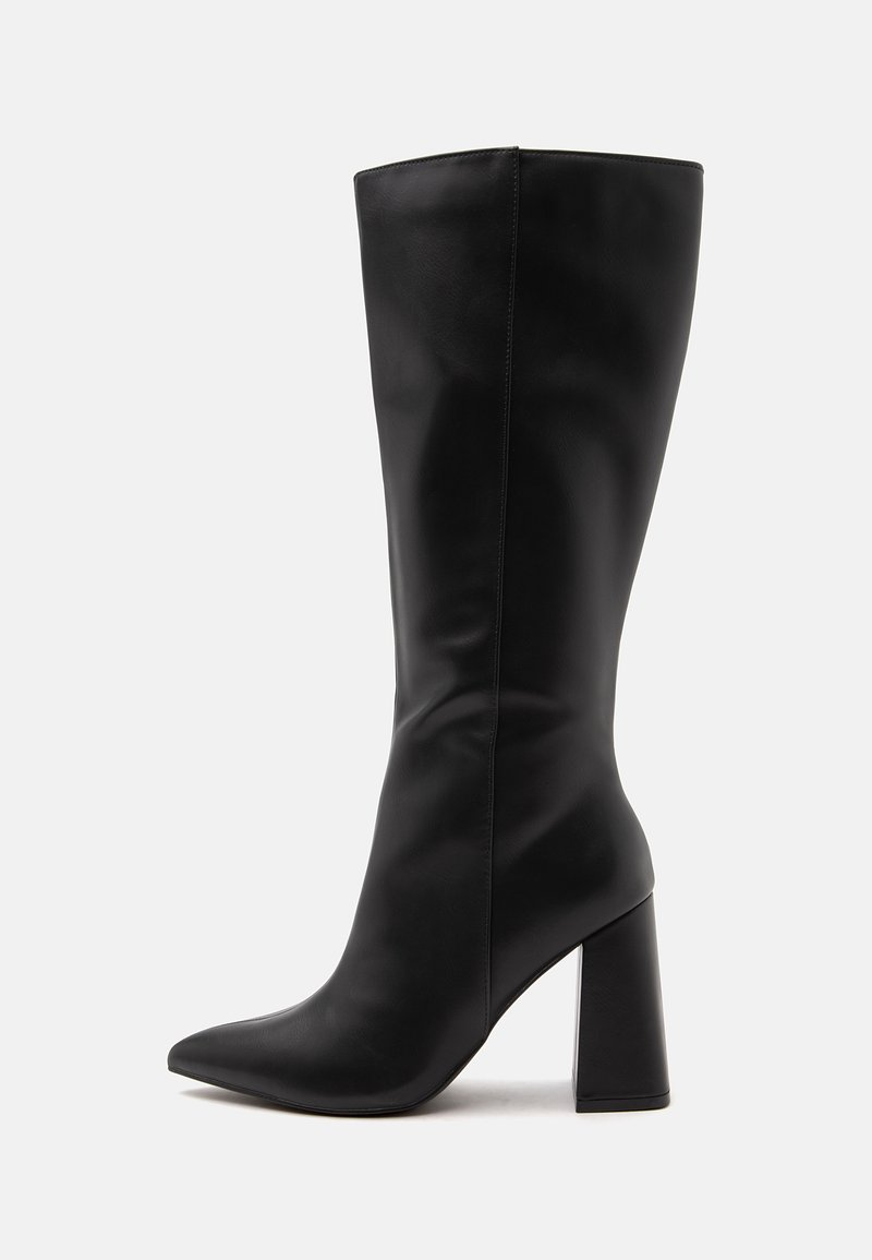 Botte haute en cuir noir avec un bout pointu et un talon haut épais sur un fond clair uni.