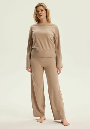 Beige knit lounge set featuring a relaxed-fit long-sleeve top and wide-leg pants with ribbed cuffs, showcasing a soft texture and seamless design.