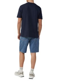 Marineblauwe katoenen T-shirt gecombineerd met lichtblauwe denimshorts. Heeft een relaxed fit, casual ontwerp en subtiele stikseldetails.