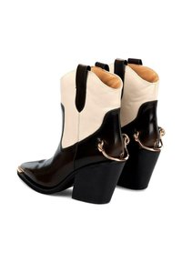 Czarno-kremowe skórzane kowbojki z ostrym noskiem, wysokim słupkowym obcasem i akcentami w złotym kolorze na obcasie.