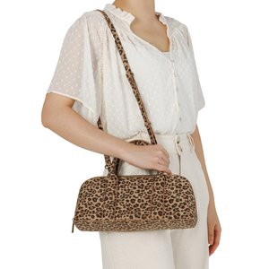 Woman wearing white blouse and pants holding a leopard-print handbag with both top handles and an adjustable shoulder strap.