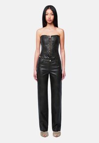Schwarzes, trägerloses Korsett-Top aus Leder mit Schnürung vorne, kombiniert mit schwarzer, gerader Lederhose mit glatter Textur.