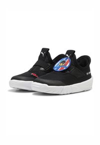 Melnas slip-on kurpes ar struktūrētu virsmu, elastīgu siksniņu, baltu gumijas zoli un apļveida logo uzlīmi, kas attēlo varoni.