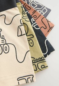 Fire par af mønstrede shorts i beige, oliven, pink og marineblå. Hver enkelt har dristige sorte linjetegninger, der viser legende designs og teksturer.