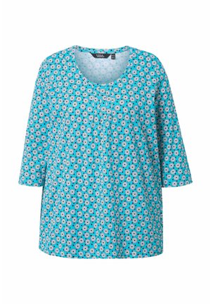 Haut à motifs floraux bleus avec des manches trois-quarts, un col rond et une coupe ample. Présente des motifs de fleurs blanches et noires sur l'ensemble.