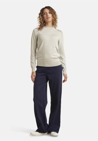 Light gray long-sleeve sweater with a round neckline, paired with navy wide-leg trousers and beige slip-on shoes. Flat texture, minimal design.