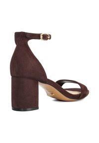 Brown suede high-heel sandal with a square toe design, wide ankle strap featuring a gold buckle, and a chunky heel. Smooth inner lining.