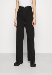 Jeans de mezclilla negros de cintura alta con un diseño de pierna recta, que cuentan con bolsillos frontales, un cierre de botón y una textura áspera.