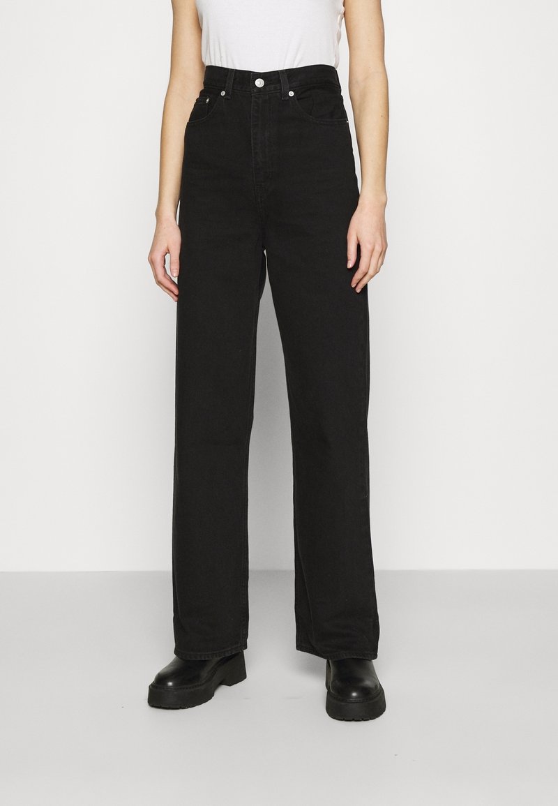 Jeans de mezclilla negros de cintura alta con un diseño de pierna recta, que cuentan con bolsillos frontales, un cierre de botón y una textura áspera.