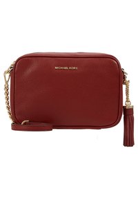 Czerwona torebka crossbody z fakturowanej skóry od Michaela Korsa z złotym łańcuszkiem i dekoracyjnym frędzlem na białym tle.