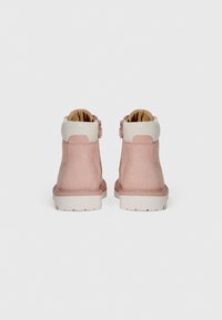Stivaletti alla caviglia in suede rosa con rifiniture in pelle bianca, caratterizzati da una texture liscia, una punta rotonda e una suola in gomma di colore chiaro.