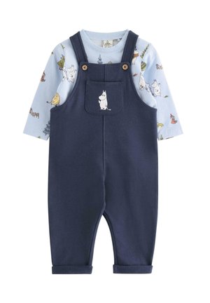 Babyblå langærmet skjorte med farverige tegneseriefigurer under marineblå overaller med en lille hvid tegneseriefigur på frontlommen.