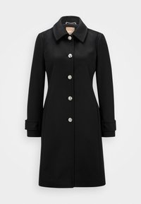 Cappotto di lana nero lungo fino al ginocchio con colletto ampio, sei bottoni metallici lungo il davanti e fasce regolabili sui polsini delle maniche lunghe.