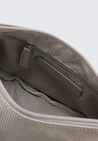 Helles beigefarbenes Innenfutter der Tasche mit einer Reißverschlusstasche und einer glatten Stoffauskleidung. Verfügt über dezente Rippungen und einen flachen Reißverschlussgriff.