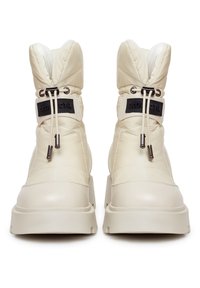 Kremowe wodoodporne botki z pikowanym wzorem, zaokrąglonym noskiem i elastycznym kołnierzem. Posiadają czarne logo i srebrne akcenty metalowe.