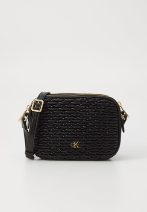 Sac bandoulière noir avec un motif de vagues texturé, quincaillerie dorée et une bandoulière amovible. Il dispose d'une fermeture zippée et d'un détail de logo sur le devant.