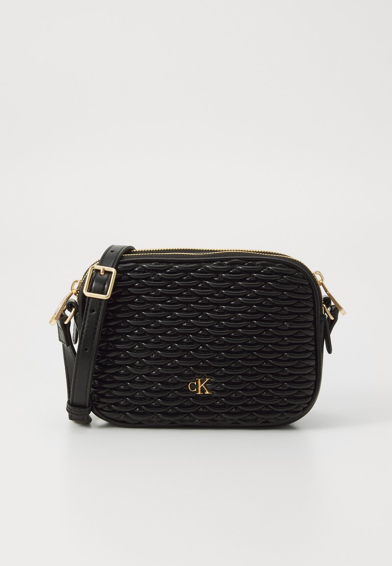 Sac bandoulière noir avec un motif de vagues texturé, quincaillerie dorée et une bandoulière amovible. Il dispose d'une fermeture zippée et d'un détail de logo sur le devant.
